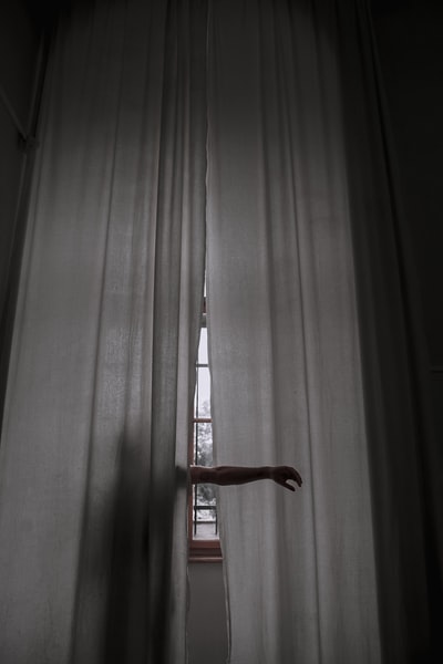 站在窗帘旁边举起手臂的人